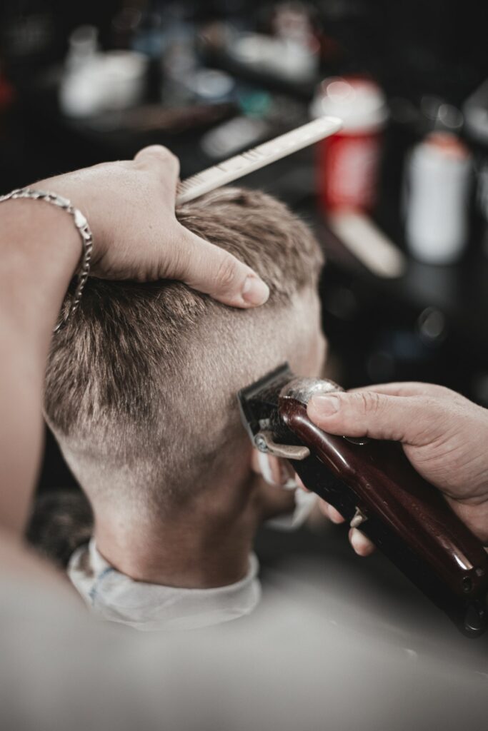 Barbero cortando el pelo a máquina en la nuca de un cliente
